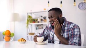 A man holding his face in pain as he experiences a dental emergency.