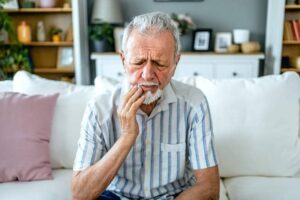 A man holds his face in pain as he experiences a dental emergency.
